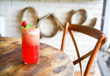 Kırmızı çilek şeffaf bir vazoda sarı çiçekler ile ahşap bir tabloda çay bobble. Arkadaki bulanık bir arka plan beyaz bir tuğla ile bir kelime - seviyorum. Bali Restoran. Yan görünümü kopya alanı.