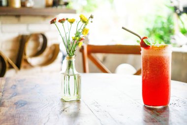 Kırmızı çilek şeffaf bir vazoda sarı çiçekler ile ahşap bir tabloda çay bobble. Arkadaki bulanık bir arka plan beyaz bir tuğla ile bir kelime - seviyorum. Bali Restoran. Yan görünümü kopya alanı.