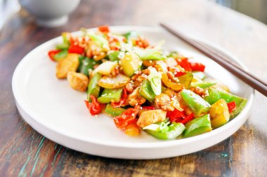 Tavuk kung pao beyaz bir tabak ve ahşap masa lambası. Çin yemeği. Yemek çubukları. Bulanık bir arka plan arka yüzünde bir beyaz tuğla yastık bir kelime sevgi ile kaplıdır. Kopya alanı ile yan görünüm