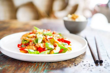 Tavuk kung pao beyaz bir tabak ve ahşap masa lambası. Çin yemeği. Yemek çubukları. Bulanık bir arka plan arka yüzünde bir beyaz tuğla yastık bir kelime sevgi ile kaplıdır. Kopya alanı ile yan görünüm