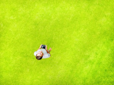 Bir adam bir yeşil çim ve gülümsüyor mutluluk ile yatıyor. En iyi hava manzaralı ve kopya alanı. Minimal tarz düz izole üzerinde orijinal yeşil çim arka plan yattı.