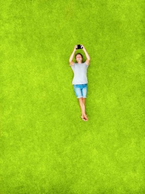 Bir adam bir yeşil çim ve gülümsüyor mutluluk ile yatıyor. En iyi hava manzaralı ve kopya alanı. Minimal tarz düz izole üzerinde orijinal yeşil çim arka plan yattı.