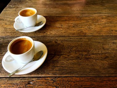 Bir kafede ahşap bir masada yan yana güçlü siyah kahve iki fincan.