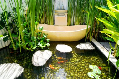 Frangipani çiçek yaprakları bir pahalı lüks şık ve spa otel Bali Ubud, yüzme carp ayakları altında yuvarlak açık banyo. Banyo iç tropik bitkiler büyümek.