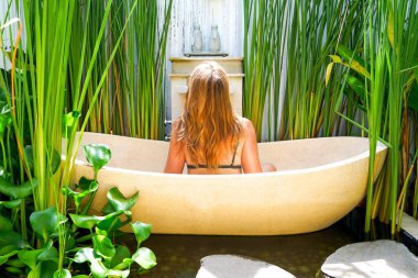 Kızıl saçlı kız çiçek-RIM ile banyoda. Bir kadın bir yuvarlak açık banyo tropik çiçekler, organik cilt bakımı, lüks spa otel Bali Ubud rahatlatır. Kopya alanı ile yan görünüm