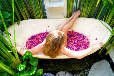 Kızıl saçlı kız çiçek-RIM ile banyoda. Bir kadın bir yuvarlak açık banyo tropik çiçekler, organik cilt bakımı, lüks spa otel Bali Ubud rahatlatır. Kopya alanı ile yan görünüm