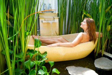 Kızıl saçlı kız çiçek-RIM ile banyoda. Bir kadın bir yuvarlak açık banyo tropik çiçekler, organik cilt bakımı, lüks spa otel Bali Ubud rahatlatır. Kopya alanı ile yan görünüm