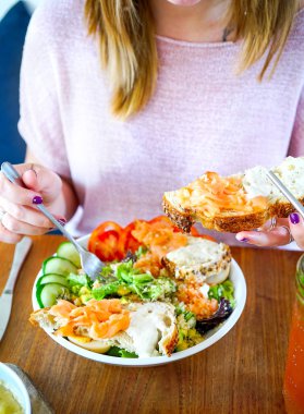 Hassas bir krem ile yumuşak ekmek dilimleri de füme somon salatası. Restoran ve ahşap bir masa. Bir kız pembe bir masada oturur ve bir salata yiyor. Kopya alanı ile yan görünüm