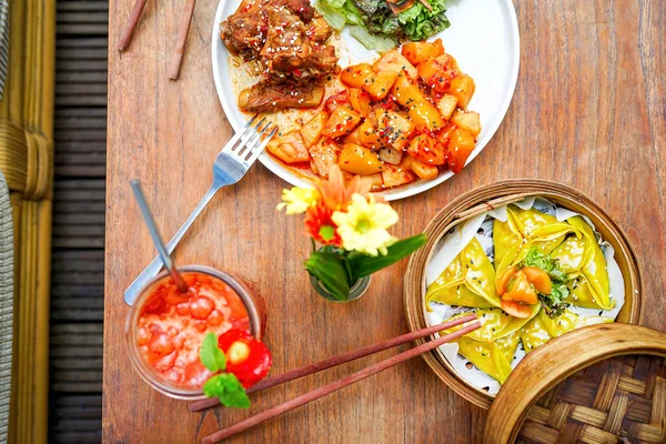 Fried pork ribs with potatoes and salad. On a white plate with a knife and fork. Dumplings and juice. Wooden background - a table. Top view with copy space