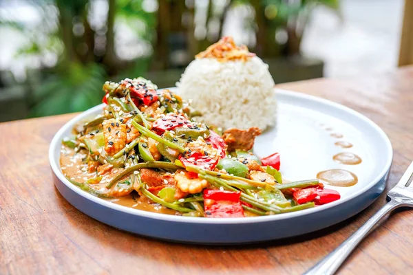 stock image Chicken kung pao on a white plate and on a light wooden table. Chinese food. Food sticks. On the back of a blurry background, a white brick pad is covered with an word love. Top view with copy space