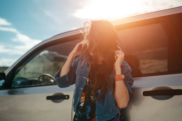 Junge Frau mit Kopfhörern posiert in der Nähe von Auto — Stockfoto