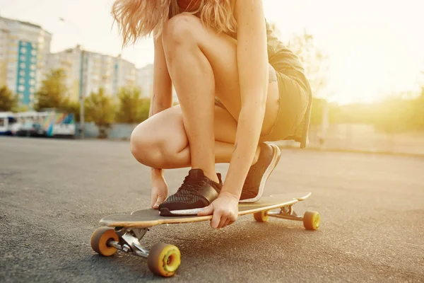 Schönes junges Mädchen mit Tattoos beim Longboard-Reiten bei sonnigem Wetter — Stockfoto