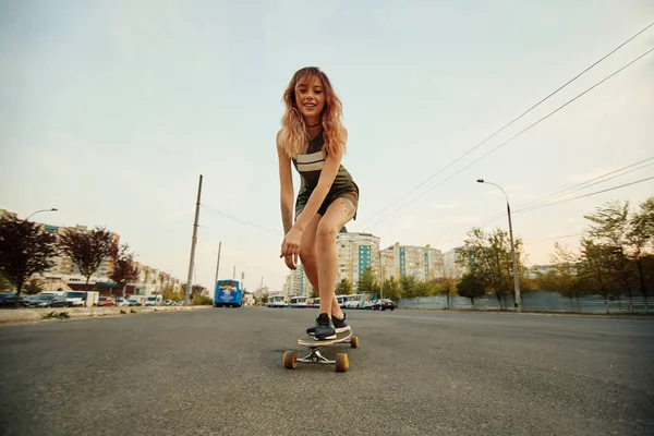 Hermosa chica joven con tatuajes montando longboard en tiempo soleado — Foto de Stock