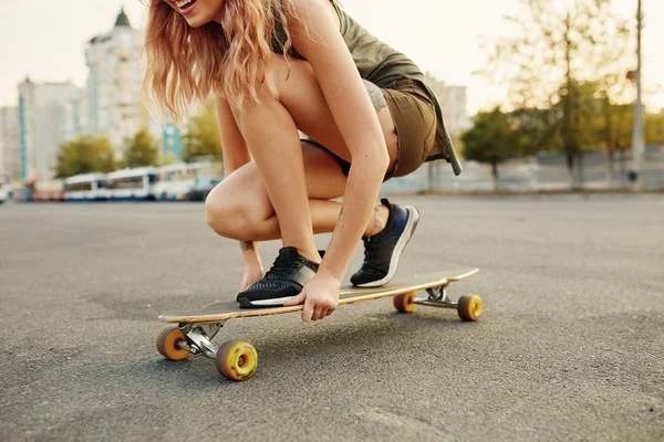 Beautiful young girl with tattoos sits on longboard — Stock Photo, Image