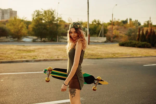 Vacker ung tatuerade flicka med longboard i soligt väder — Stockfoto
