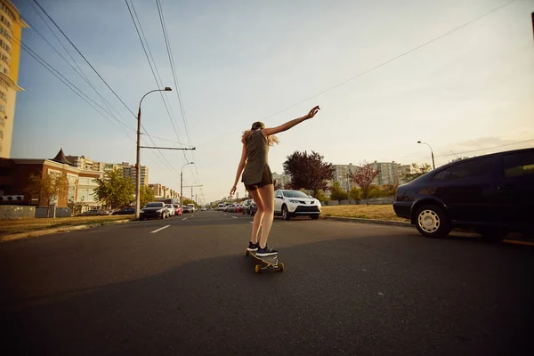 Schönes junges Mädchen mit Tattoos beim Longboard-Reiten bei sonnigem Wetter — Stockfoto