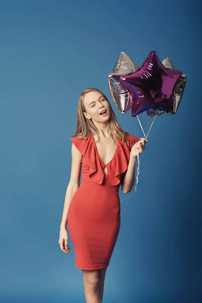 Vrouw in rode jurk houden ballonnen. — Stockfoto