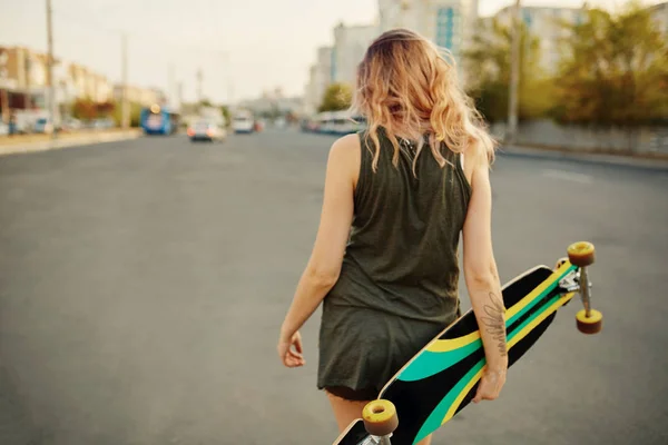 Krásná mladá Tetovaný dívka s longboard za slunečného počasí — Stock fotografie