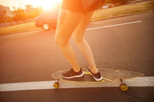 Menina bonita com tatuagens montando longboard em tempo ensolarado — Fotografia de Stock