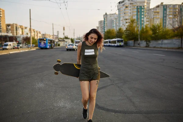 Beautiful young tattooed girl with longboard in sunny weather — Stock Photo, Image