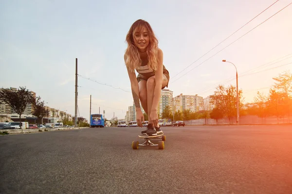 Krásná mladá dívka s tetováním na koni longboard za slunečného počasí — Stock fotografie