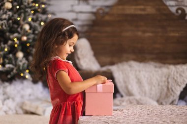 Gülümseyen ve pembe mevcut kutu tutan küçük şirin kız