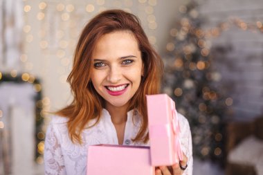Mutlu genç bir kadın Noel hediyesi kutusunu açıyor.