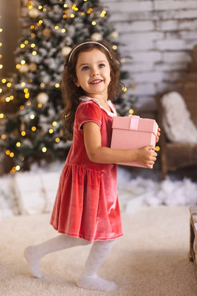 Pequena menina bonito sorrindo e segurando caixa de presente rosa — Fotografia de Stock