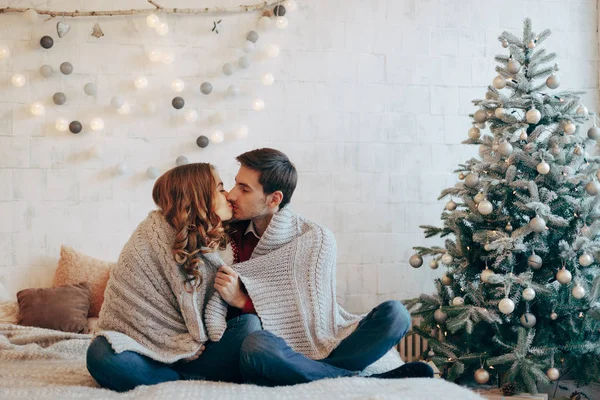 Jeune couple embrasser enveloppé dans une couverture le soir de Noël — Photo