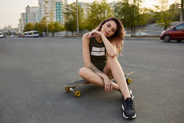 Young girl in short shorts sitting on longboard — Stock Photo, Image