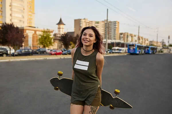 Bella ragazza con tatuaggi in posa con un longboard colorato — Foto Stock