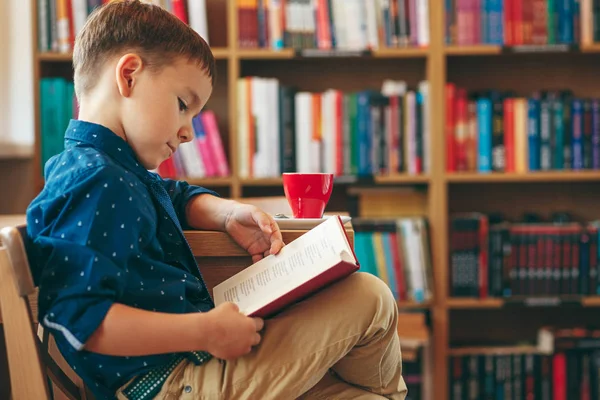 Reading boy with cup of tea — Stock Photo, Image