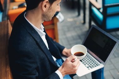 Genç yakışıklı adam zevk kahve çalışma üstünde laptop