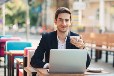 Genç yakışıklı adam zevk kahve çalışma üstünde laptop