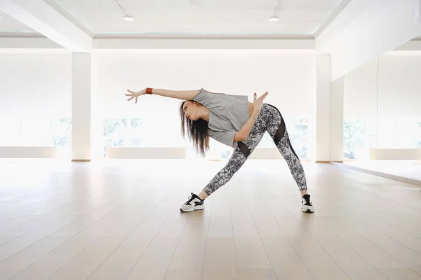 Athletic young girl performing sports and dance alone in a studio