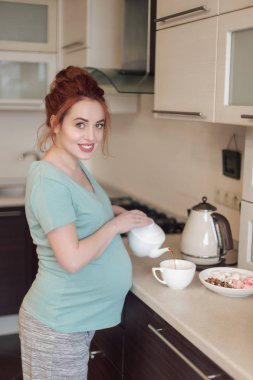 Gülümseyen hamile kadın dökme çay
