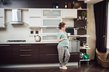 Evde rahatlatıcı bir bardak çay ile güzel bir hamile kadın