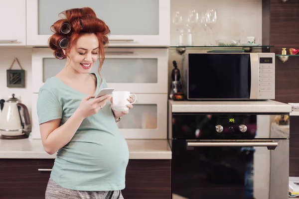 Usmívající se těhotná žena pomocí chytrého telefonu — Stock fotografie