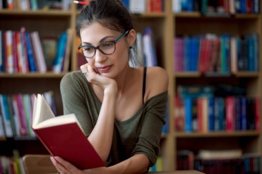 Bir kitap okuma gözlüklü genç gülümseyen kadın