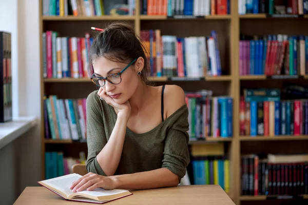 Молодая женщина в очках читает книгу — стоковое фото