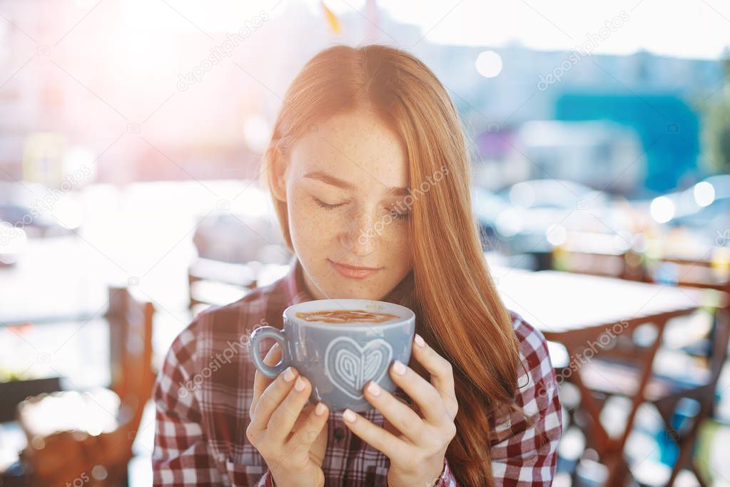 Beautiful girl enjoying the coffee aroma with closed eyes