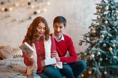 Gülümseyen kadın erkeğini alınan bir Noel hediyesi açma.