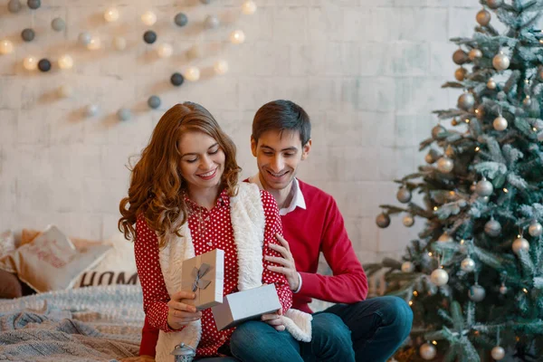 Mujer sonriente abriendo un regalo de Navidad recibido de su hombre . —  Fotos de Stock