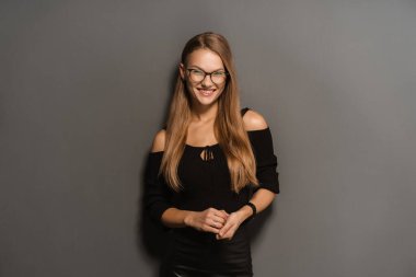 Siyah arka planda gözlüklü zarif, gülümseyen kadın.