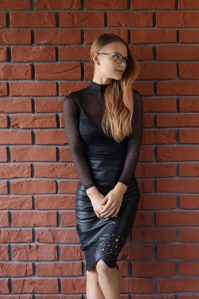 Elegante lächelnde Frau mit Brille vor Backsteinmauer-Hintergrund — Stockfoto