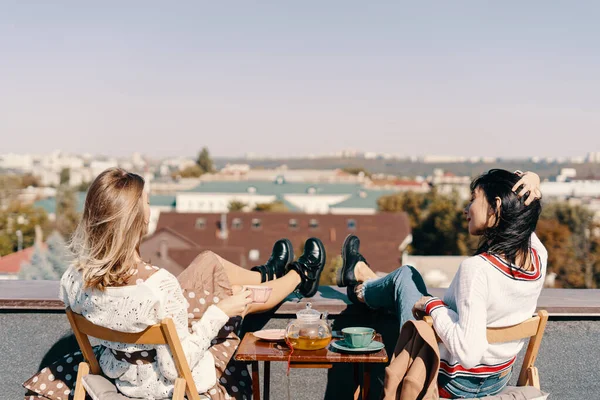 Duas meninas atraentes desfrutar de uma festa de chá no telhado com vista para a cidade — Fotografia de Stock