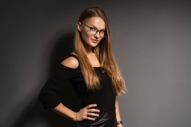 Siyah arka planda gözlüklü zarif, gülümseyen kadın.