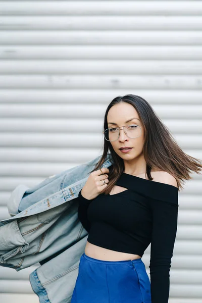 Retrato jovem com óculos. Mulher de estilo bonito com cabelo escuro longo vestindo uma jaqueta de ganga — Fotografia de Stock