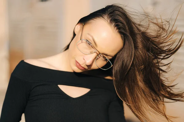 Atraktivní mladá brunetka žena v černé horní a průhledné brýle pózovat na ulici — Stock fotografie