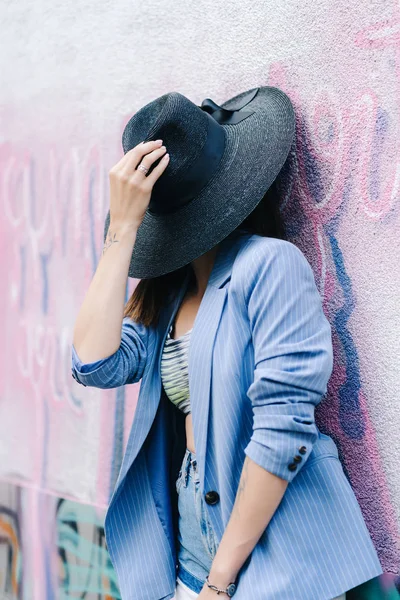 Retrato de moda de una joven vestida con una chaqueta de rayas azules y un sombrero negro — Foto de Stock